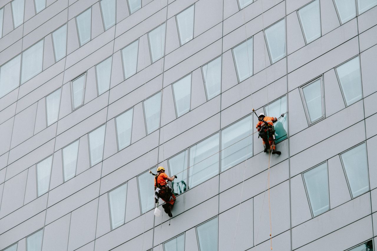 gallery-02 High-rise window washers in safety gear cleaning a skyscraper facade.